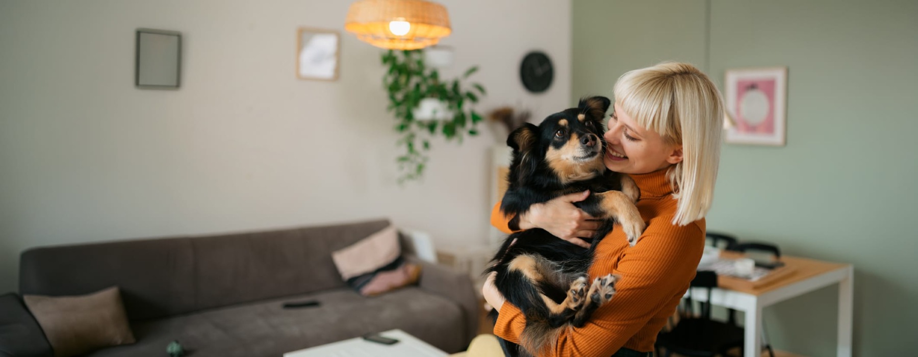 a woman smiling and holding her pet indoors